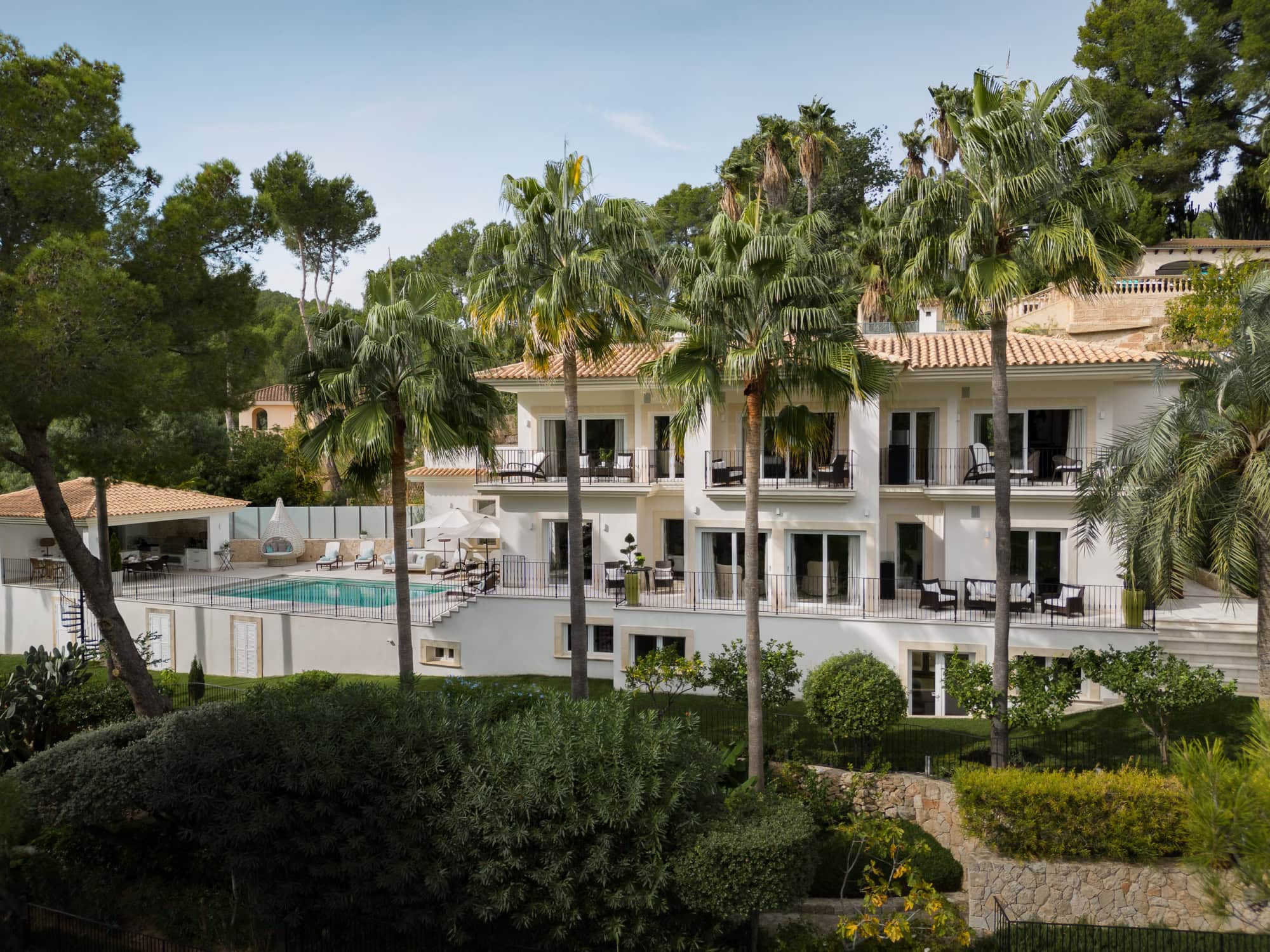 Luxury villa with swimming pool surrounded by lush greenery and palm trees in a tropical setting.